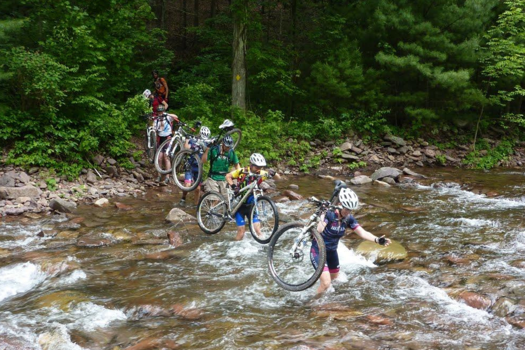 Bikers carrying bikes through water