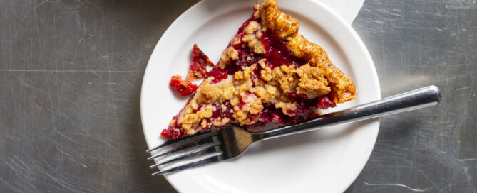 A slice of pie sitting on a white plate with a silver fork.