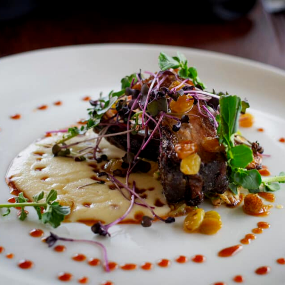 Meat and greens beautifully plated on a white plate.