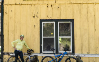 Person standing with bikes Infront of a building with a sign saying Stokesville