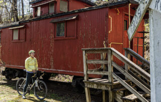 Cyclist next to a old red railroad car
