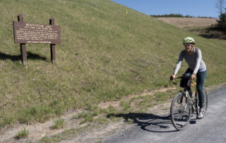 Cyclist on road Next to Hearthstone lake sign