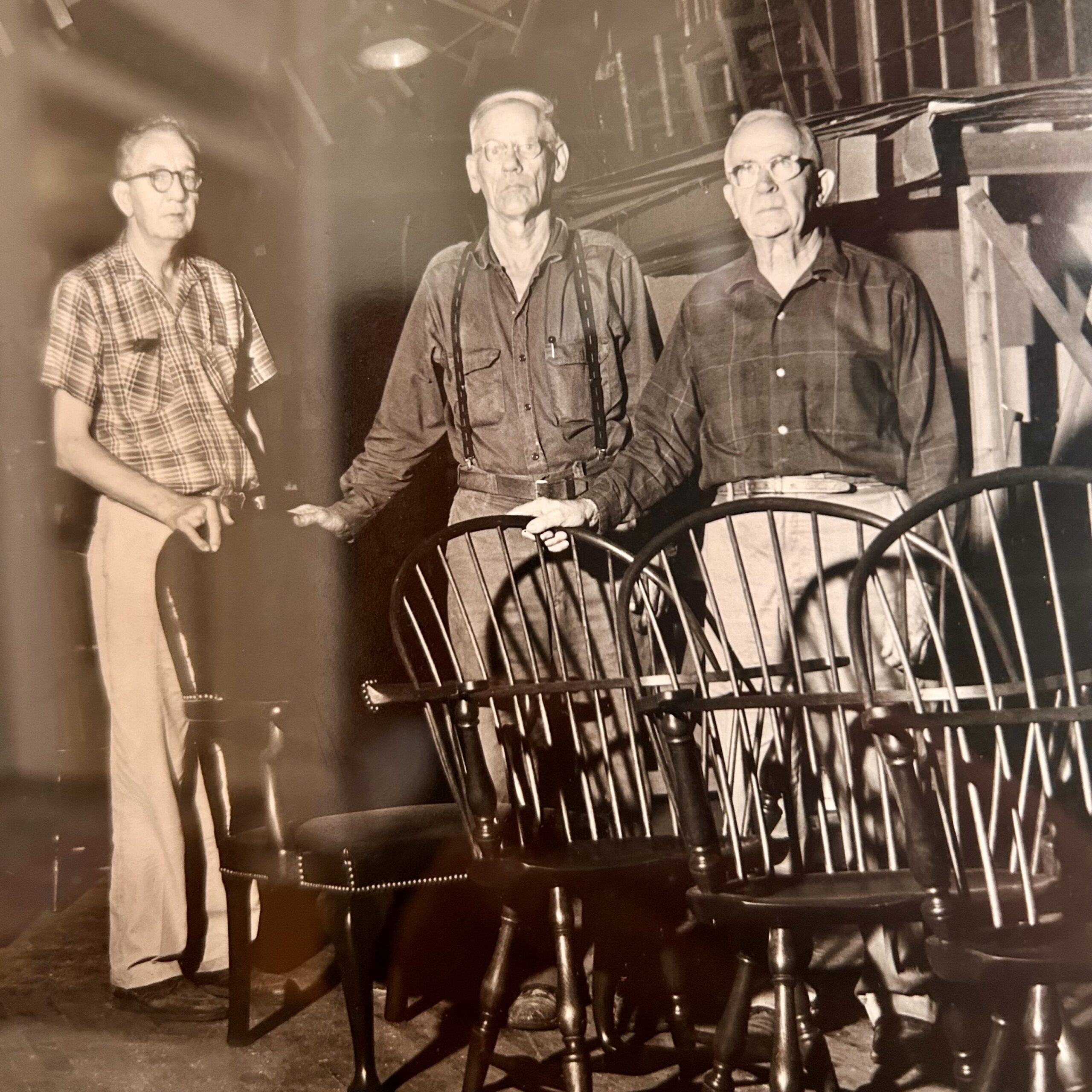Three men with the Virginia Craftsmen standing with wooden chairs