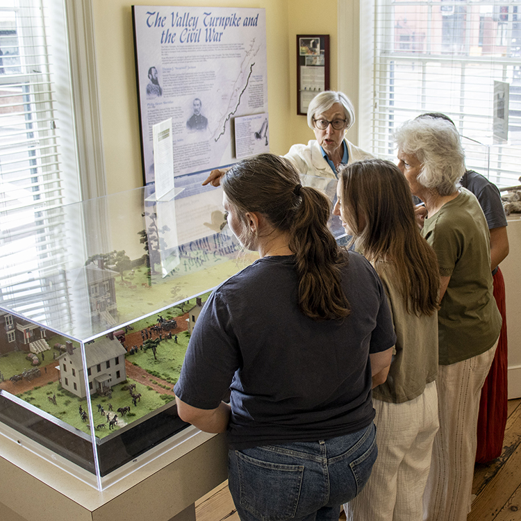 House Tour 4_square Ladies standing around miniature display in turnpike museum