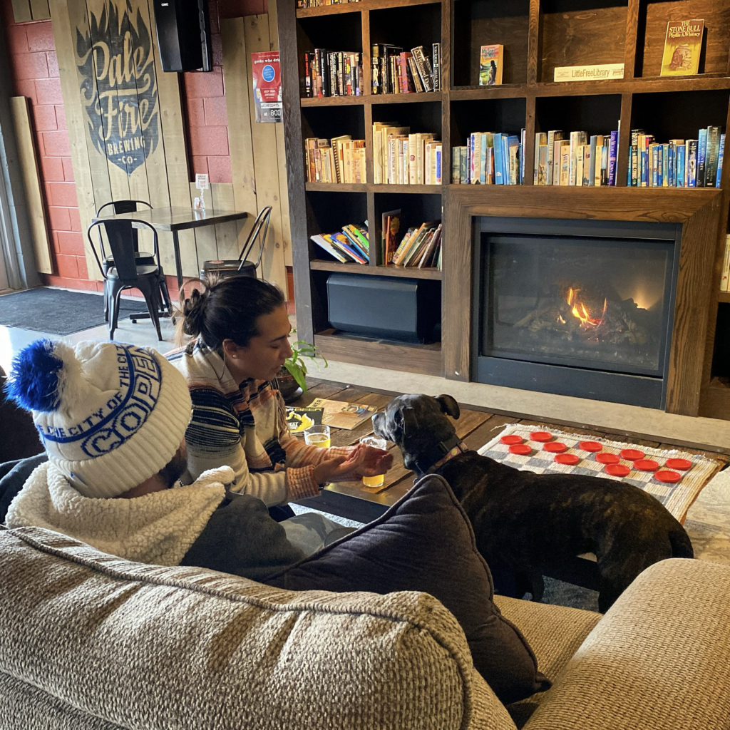 Pale Fire_fireplace_square People and a dog sitting in front of a fire at Pale Fire