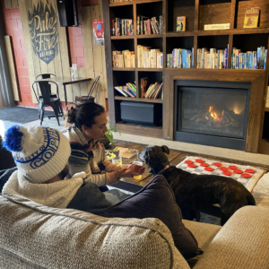 People and a dog sitting in front of a fire at Pale Fire