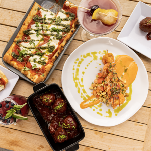 a table full of food from flat bread to meatballs and a cocktail
