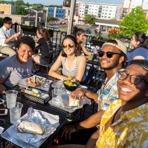Four people enjoying Magnolia's tacos on a rooftop dining area