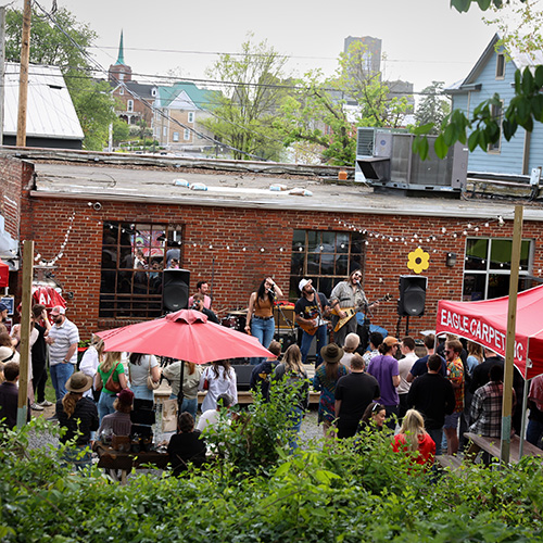 Band and a crowd in a courtyard surrounded by greenery
